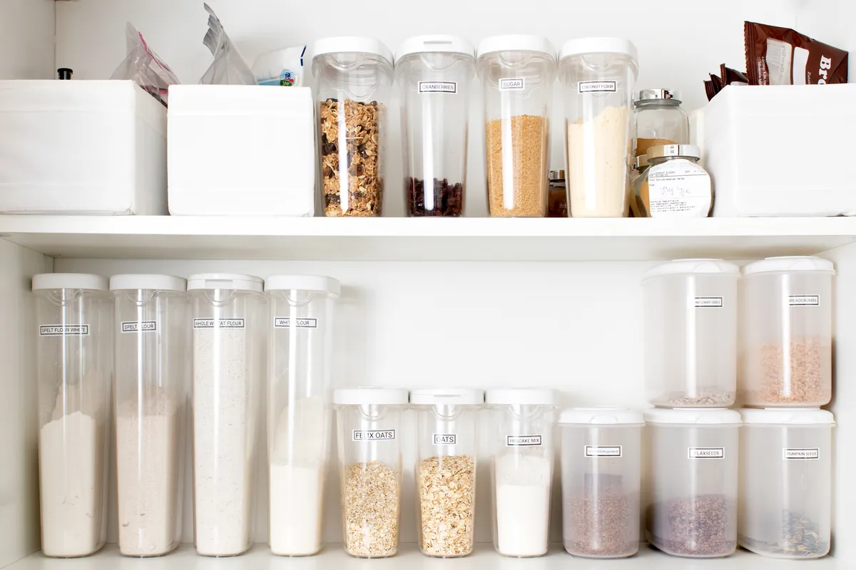 Pantry shelves with labelled clear containers of grains, cereals and flour
